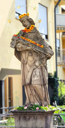 021_005 Die Skulptur eines Heiligen ist geschmückt mit Blumen
