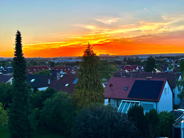 023_003 Ein außergewöhnlich farbintensiver Sonnenuntergang hinter Häusern und einer großen weiten Ebene