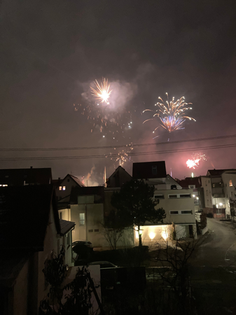 028_005 Ein Feuerwerk beleuchtet den Abendhimmel über mehreren Häusern